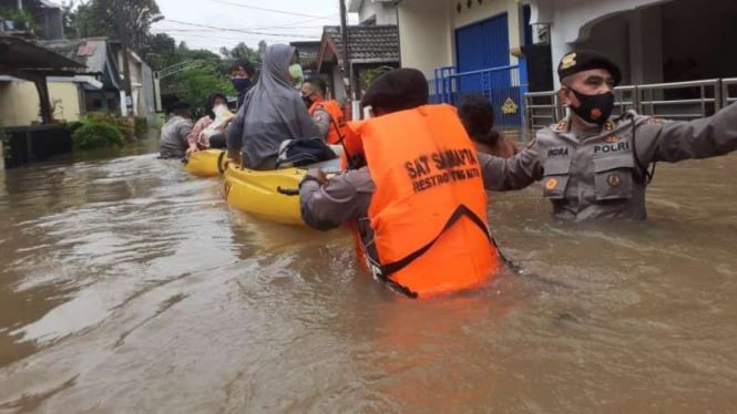 Petugas kepolisian membantu mengevakuasi warga yang kebanjiran di Rawa Buaya.