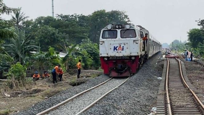 Uji coba rangkaian kereta api melintasi rel yang telah selesai diperbaiki akibat banjir.