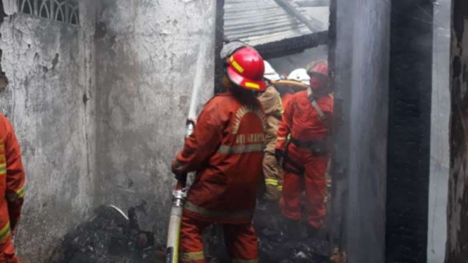 Petugas tengah memadamkan api yang membakar sebuah rumah di Setiabudi.