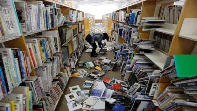 Dokumentasi - Seorang staf perpustakaan mencoba merapikan buku-buku yang berjatuhan dari rak akibat gempa bumi kuat di Kota Iwaki di Iwaki, Prefektur Fukushima, Jepang, 14 Februari 2021.