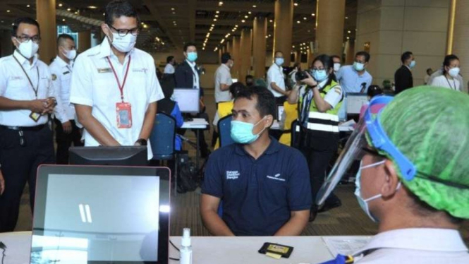 Menteri Pariwisata dan Ekonomi Kreatif Sandiaga Salahuddin Uno (ketiga kiri) meninjau pelaksanaan vaksinasi COVID-19 pada petugas bandara di Bandara Internasional I Gusti Ngurah Rai, Badung, Bali, Senin, 22 Maret 2021.