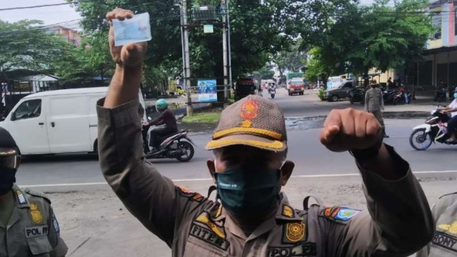 Seorang oknum Satpol PP di Lombok Timur memperlihatkan KTP seorang warga yang terjaring razia penggunaan masker di Mataram, Nusa Tenggara Barat, Senin, 22 Maret 2021.