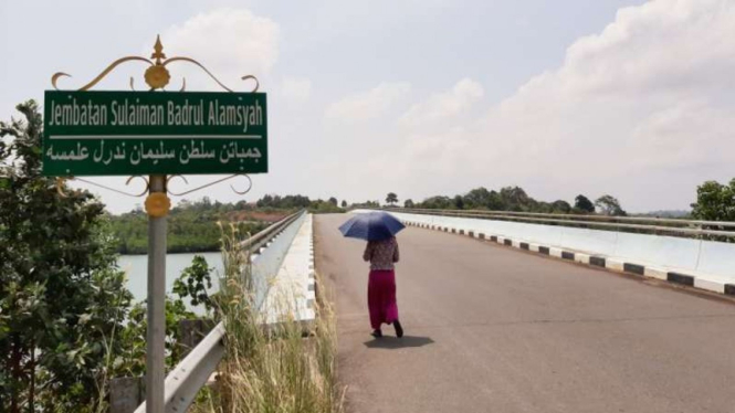 Warga berjalan di bawak terik matahari melintasi jembatan Dompak, Tanjungpinang, Kepulauan Riau.