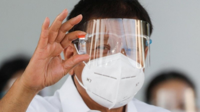 Presiden Filipina Rodrigo Duterte memegang sebotol vaksin virus corona.