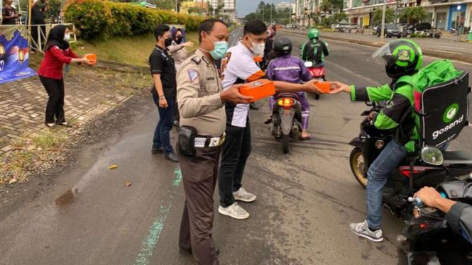 Petugas Samsat Kabupaten Tangerang bagi-bagi takjil ke pengendara motor.