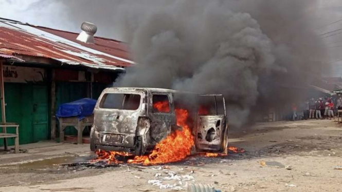 Satu unit mobil milik pelaku penganiayaan di pasar sentral Remu, Kota Sorong, Papua Barat, yang dibakar oleh massa, Senin sore, 19 April 2021.