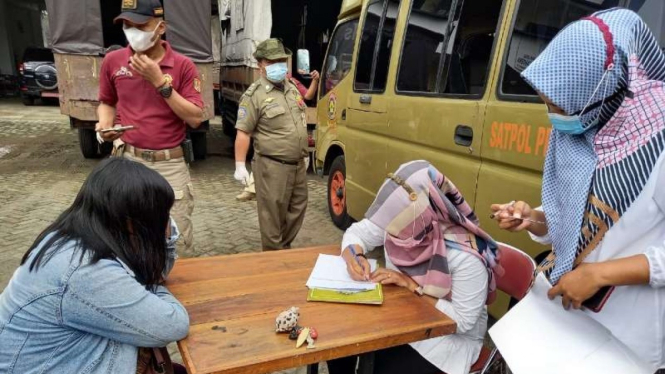 Petugas Satpol PP Kota Semarang memeriksa identitas seorang wanita yang disebut pekerja seks komersial (PSK) yang terjaring operasi razia pengemis dan gelandangan di Kota Semarang, Jawa Tengah, Rabu, 28 April 2021.