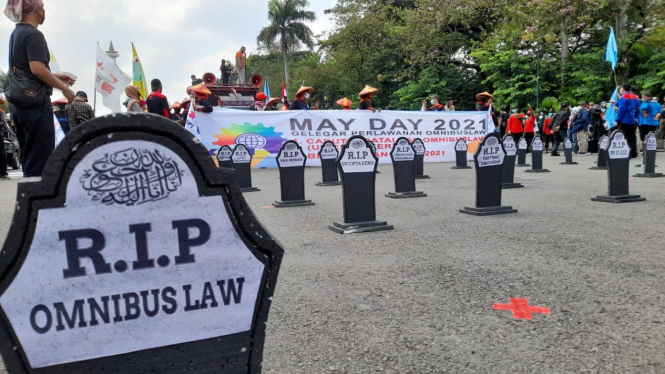 Batu nisan bertuliskan RIP Omnibus Law dalam aksi hari buruh di kawasan Monas.