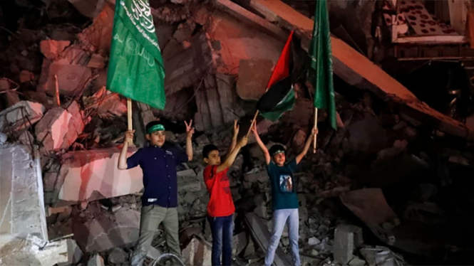 Rakyat Palestina merayakan kemenangan dengan latar puing-puing bangunan gedung