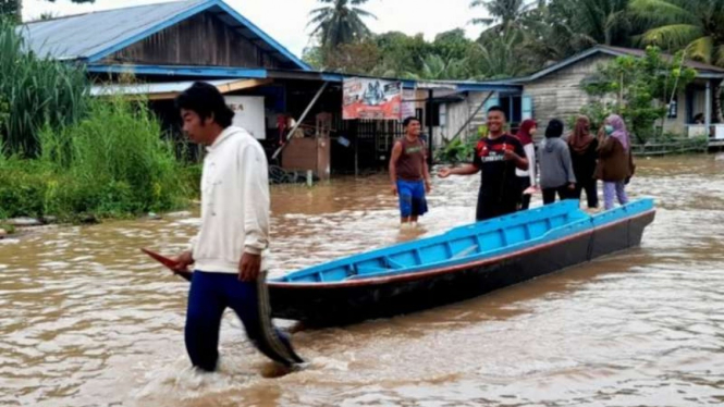 Seorang pria membawa sampan di tengah banjir yang melanda delapan desa di Kabupaten Nunukan, Kalimantan Utara, Sabtu, 29 Mei 2021.