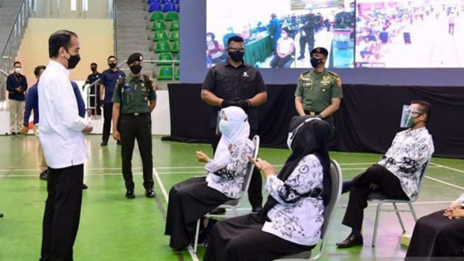 Presiden Joko Widodo berbicara dengan sejumlah guru saat meninjau vaksinasi massal di Gelanggang Olahraga Remaja, Kecamatan Marpoyan Damai, Kota Pekanbaru, Riau, pada Rabu, 19 Mei 2021.