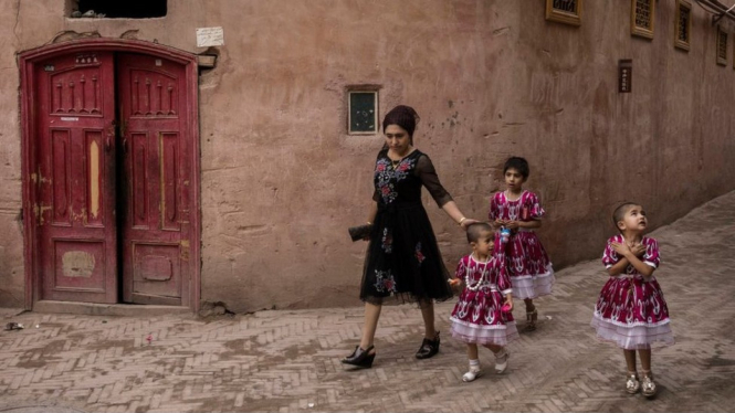 Seorang perempuan berjalan di kota tua Kashgar di Xinjiang, di mana China mendapat tuduhan untuk mengurangi angka kelahiran dari etnis minoritas. BBC Indonesia