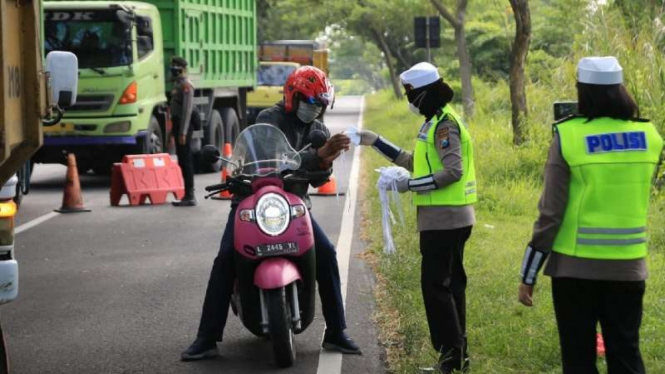 Sejumlah polisi wanita yang dijuluki Srikandi Polda Jawa Timur membagikan masker kepada pengendara di satu ruas jalan di Kabupaten Bangkalan, Rabu, 9 Juni 2021, menyusul lonjakan kasus penularan COVID-19 di daerah itu.