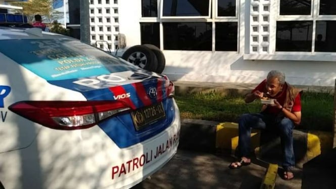 Gubernur Jawa Tengah Ganjar Pranowo menyantap bekal makanan di area parkir mobil di kantor Polisi Jalan Raya gerbang tol Pemalang, di sela-sela kegiatannya memantau pelaksanaan PPKM, Minggu, 4 Juli 2021.