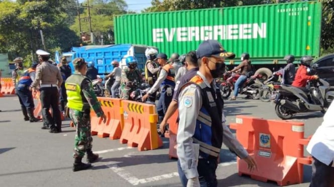 Petugas gabungan menutup total akses masuk utama menuju Kota Surabaya, Jawa Timur, di titik penyekatan Bundaran Waru pada Rabu, 7 Juli 2021.