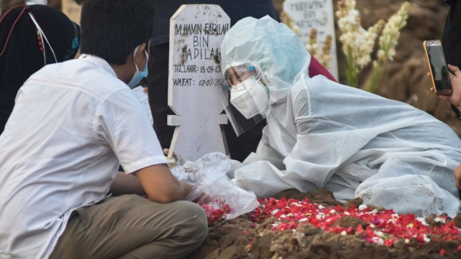 Anggota keluarga mengenakan pakaian APD menangisi korban Covid-19 di TPU Rorotan, Cilincing, Jakarta, 8 Juli 2021.  Getty Images/BBC Indonesia