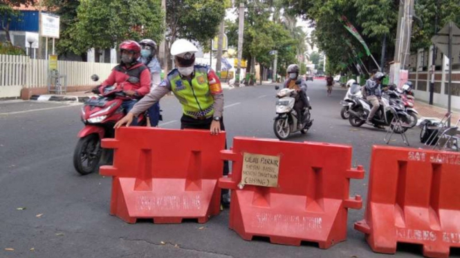 Seorang petugas dari Polres Kudus, Jawa Tengah, bersama Dinas Perhubungan dan TNI mulai membuka penyekatan akses menuju Alun-alun Kudus di Jalan Sunan Muria, Selasa, 3 Agustus 2021.