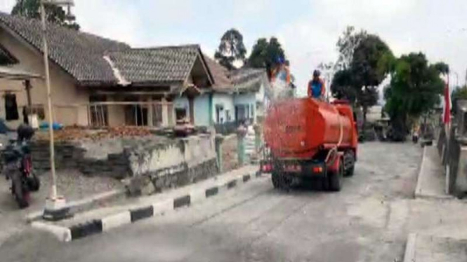 Petugas BPBD Kabupaten Boyolali dengan truk tangki air membersihkan sisa abu vulkanik dampak erupsi Gunung Merapi di jalan Desa Klakah, Kecamatan Selo, Kabupaten Boyolali, Jawa Tengah, Jumat, 13 Agustus 2021.