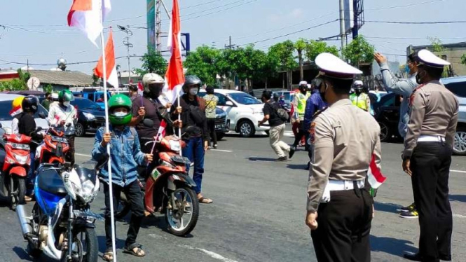 Sejumlah pengendara kendaraan bermotor di Surabaya berhenti sejenak untuk menghormati Sang Saka Merah Putih saat peringatan HUT ke-76 RI pada Selasa, 17 Agustus 2021.