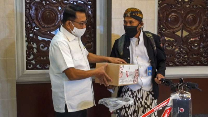 Kepala Staf Kepresidenan Moeldoko saat memberikan hadiah sepeda dari Presiden Joko Widodo kepada pejalan kaki asal Wonosobo, Mahmudin, di Gedung Bina Graha, Jakarta, Rabu, 18 Agustus 2021.