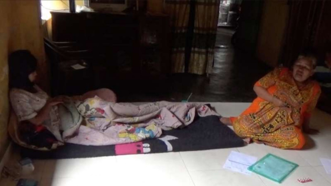 Seorang mahasiswi (kiri, setengah berbaring) di Pariaman, Sumatera Barat, dirawat di rumahnya dan ditemani ibunya setelah mengalami pembengkakan payudara setelah disuntik vaksin COVID-19 pada Sabtu, 21 Agustus 2021.