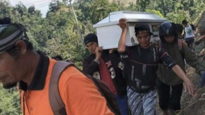 Jenazah warga digotong oleh sejumlah warga lainnya dari pusat Kota Palu menuju rumah Kecamatan Lindu, Kabupaten Sigi, Sulawesi Tengah, sejauh 15 kilometer, pada Senin, 30 Agustus 2021, karena akses jalan terputus akibat longsor.