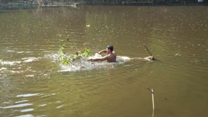 Warga tengah mencari ikan di Sungai Bengawan Solo yang tercemar limbah ciu.
