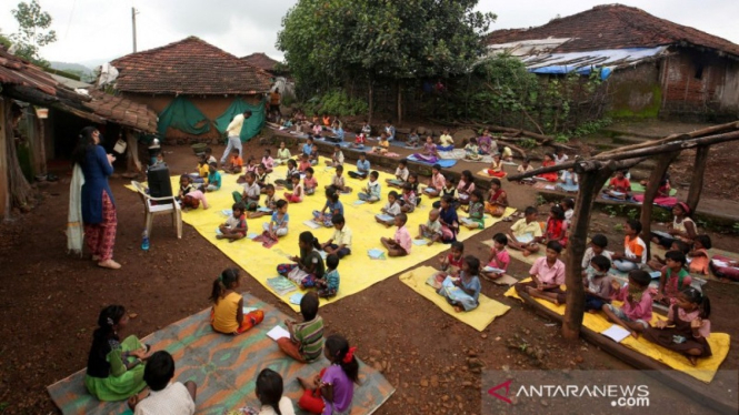 Anak-anak India menjaga jarak sosial saat mendengarkan pelajaran.