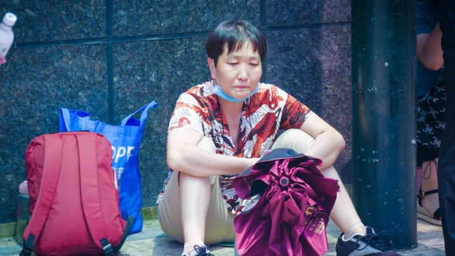 Seorang warga China duduk di luar kantor pusat Evergrande di Shenzen, menunggu kepastian uangnya di perusahaanÂ raksasa properti itu.Â  (ABC News: Paddy Fok)