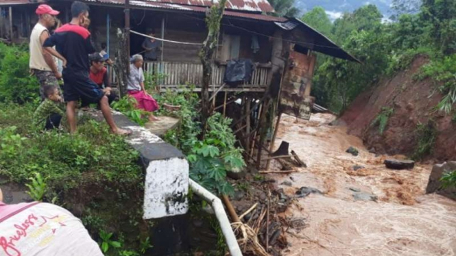 Sejumlah warga menyaksikan arus deras air banjir bandang di Kabupaten Empat Lawang, Sumatera Selatan, Minggu, 26 September 2021.