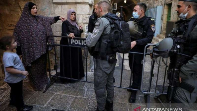 Seorang warga berbicara dengan sejumlah polisi perbatasan Israel saat mereka ber