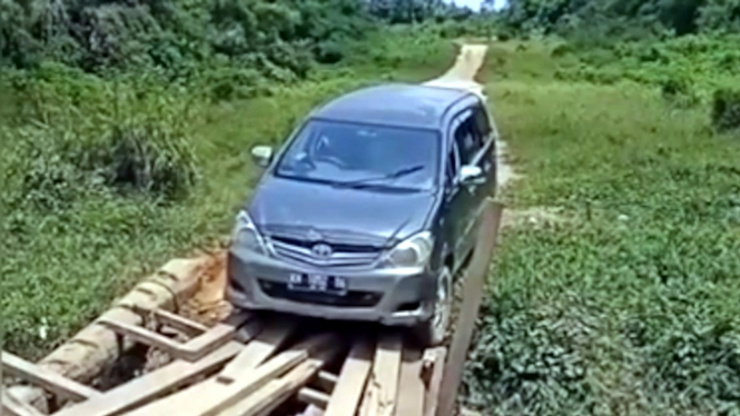 Mobil Toyota Innova melewati jembatan rusak.