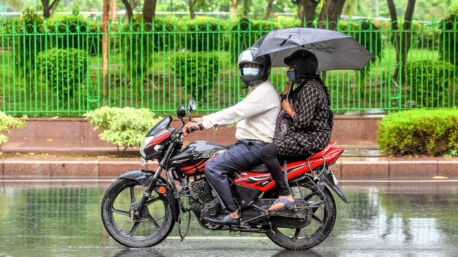 Ilustrasi naik motor sambil membawa payung.