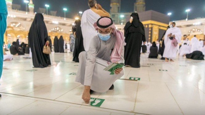 Petugas mencabut stiker jaga jarak di masjidil haram