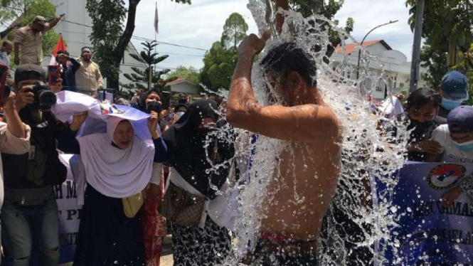 Sejumlah warga korban banjir rob di Belawan, Kota Medan, Sumatera Utara, berdemonstrasi dengan mandi menggunakan air laut di depan Kantor Gubernur, Senin, 18 Oktober 2021, untuk menuntut pemerintah segera membereskan permasalahan banjir.