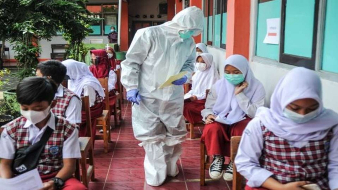 Petugas kesehatan memberikan nomor antrean kepada siswa untuk menjalani pemeriksaan COVID-19 di SD Negeri 025 Cikutra, Bandung, Jawa Barat, Jumat, 22 Oktober 2021.