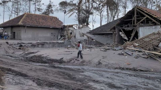Salah seorang warga Dusun Sumbersari, Desa Supiturang, Kecamatan Pronojiwo, Kabupaten Lumajang, Jawa Timur, melintas rumah rusak akibat terjangan awan panas guguran Gunung Semeru, Rabu, 8 Desember 2021.