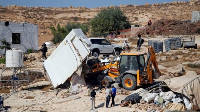 Sebuah buldoser Israel menghancurkan sebuah bangunan Palestina di Tepi Barat.