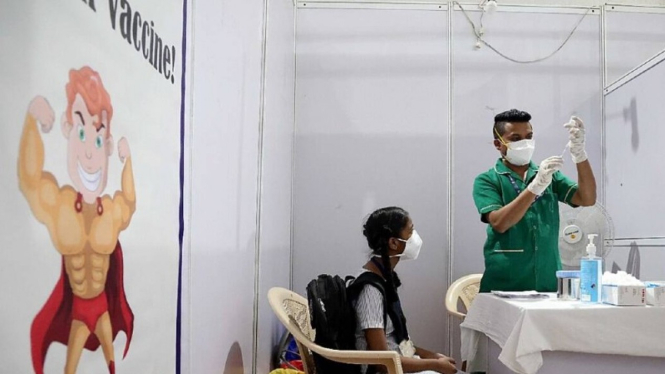 Seorang perawat India memberikan vaksin COVID-19 kepada seorang siswa.
