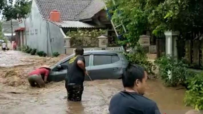 Warga mengevakuasi sebuah mobil yang terseret derasnya banjir di Perumahan Bumi Mangli Permai di Kabupaten Jember, Jawa Timur, Minggu, 9 Januari 2022.