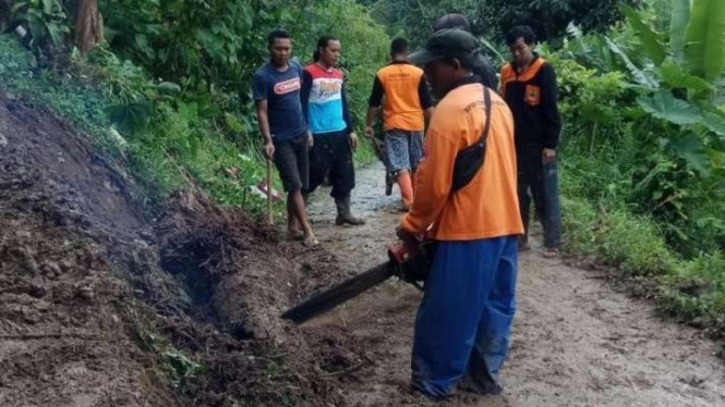 Petugas mengevakuasi material tanah longsor yang menutupi akses jalan warga di Desa Japan, Kecamatan Dawe, Kabupaten Kudus, Jawa Tengah, Rabu, 12 Januari 2022.