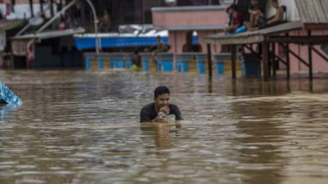 Seorang warga berjalan di tengah banjir yang merendam Kecamatan Pengaron, Kabupaten Banjar, Kalimanta Selatan, pada Rabu siang, 12 Januari 2022.