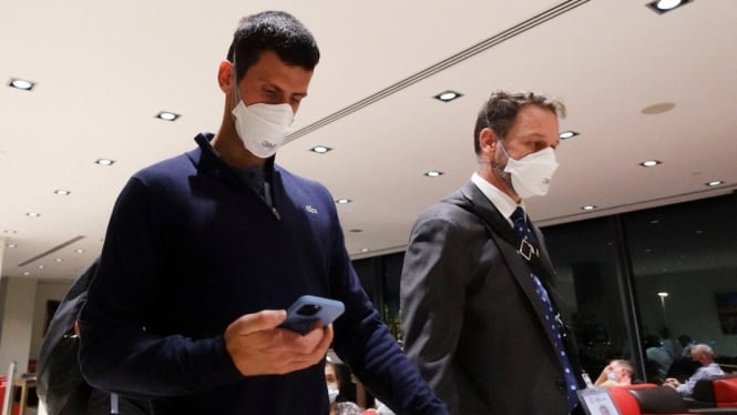 Novak Djokovic saat berada di bandara Melbourne untuk penerbangan kembali ke negaranya, Minggu malam (16/01). (Reuters: Loren Elliott)