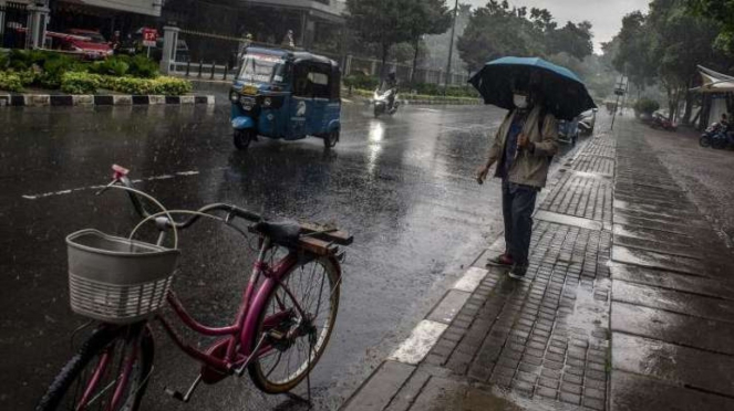 WARGA Berjalan Menggunakan Payung Saat Hujan Di Jakarta. (Foto ilustrasi).