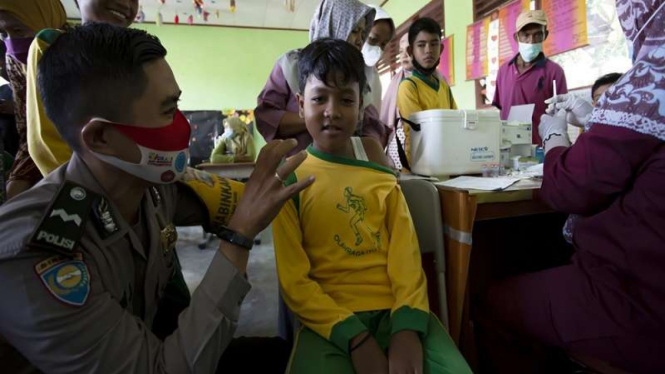 Personel Bhabinkamtibmas menghibur anak yang mengikuti vaksinasi