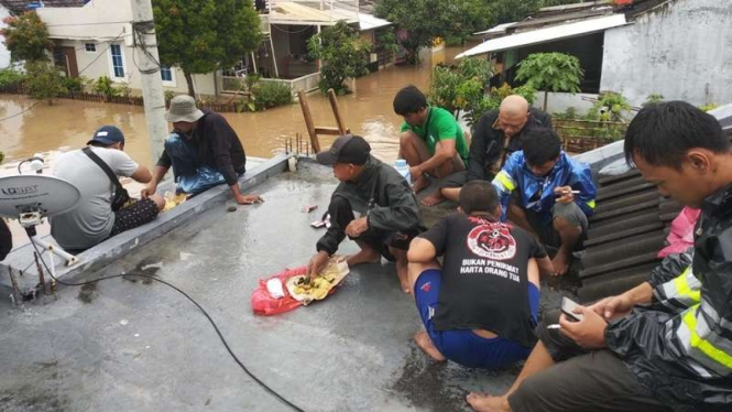 Sejumlah warga berada di atap rumah karena banjir di Serang, Banten