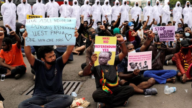 Polisi mengenakan APD menjaga unjuk rasaÂ  warga Papua dan aktivis lainnya di dekat Monas di Jakarta 1 Desember 2021. (REUTERS/Willy Kurniawan)