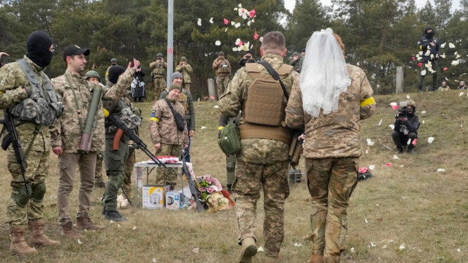 Tentara cadangan Ukraina melemparkan bunga ke pasangan yang menikah di garis depan. (AP:Â Efrem Lukatsky)