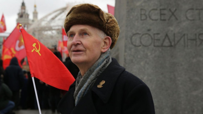 Seorang lelaki tua memegang bendera Uni Soviet. Getty Images via BBC Indonesia