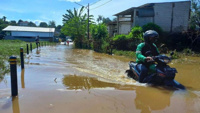 Pengendara memaksa terobos banjir yang menggenangi Jalan Kp. Bulak Barat, Depok.